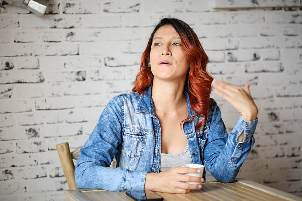 Young woman sitting at a table in a cozy cafe, enjoying coffee while engaged in lively conversation and sharing ideas with friends