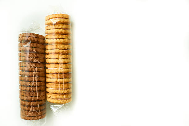 Stock photo showing close-up, elevated view of an assortment of luxury collection of Belgian chocolate biscuits in a disposable, single use plastic tray inset of a biscuit tin, pictured against a mottled blue background.