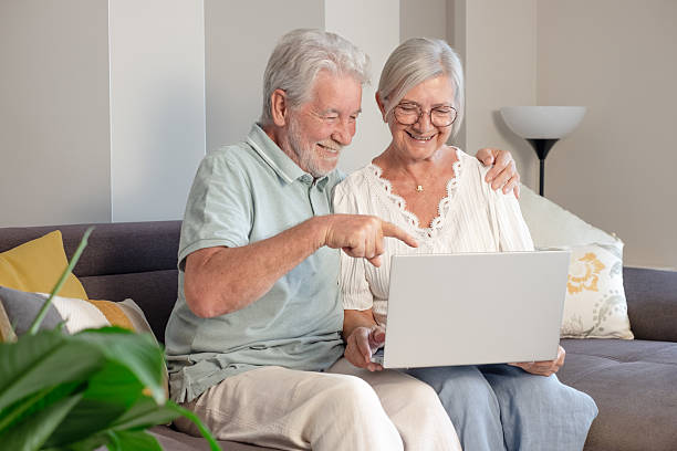 istock Happy bonding senior retired couple sitting on sofa using laptop technology together planning travel or common future, enjoying peaceful moment at home. 2216936302