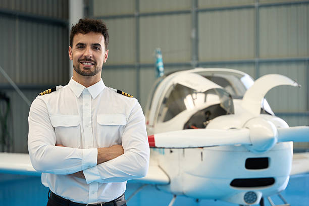 istock Smiling pilot posing with arms crossed in front of small airplane 2216943230