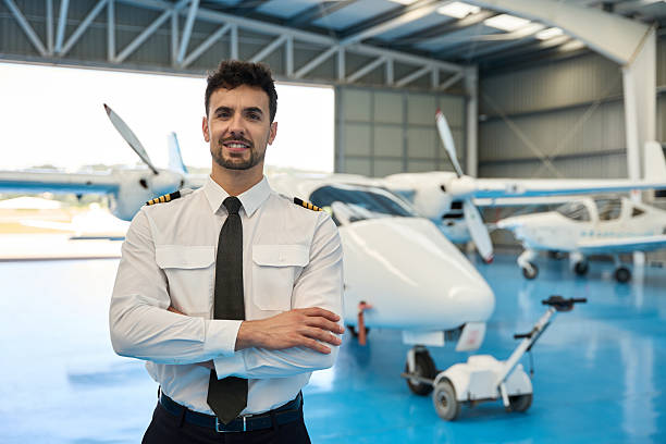 istock Confident pilot smiling with arms crossed in aircraft hangar 2216943236