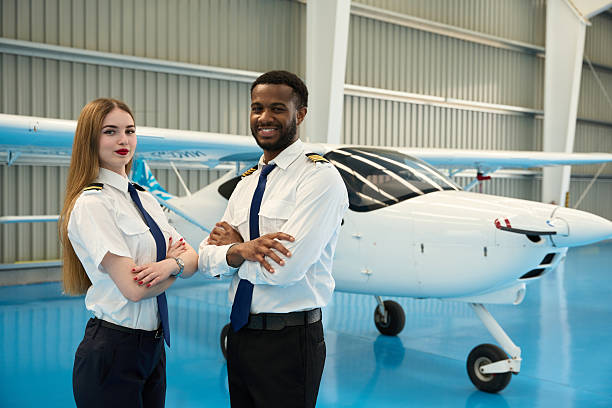 istock Smiling pilot students posing with arms crossed in aircraft hangar 2216943480