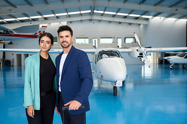 istock Student pilots smiling in aircraft hangar with suitcase 2216943616