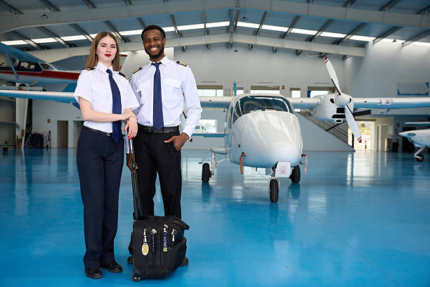 istock Smiling student pilots posing in aircraft hangar 2216943625