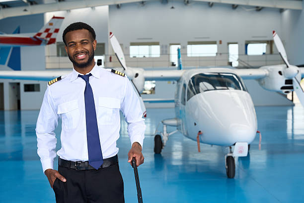 istock Smiling pilot posing in aircraft hangar with suitcase 2216943650