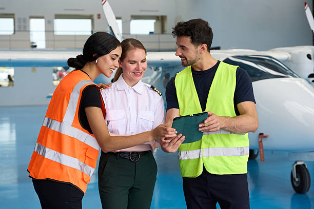 Aircraft mechanics and student pilot using tablet in hangar