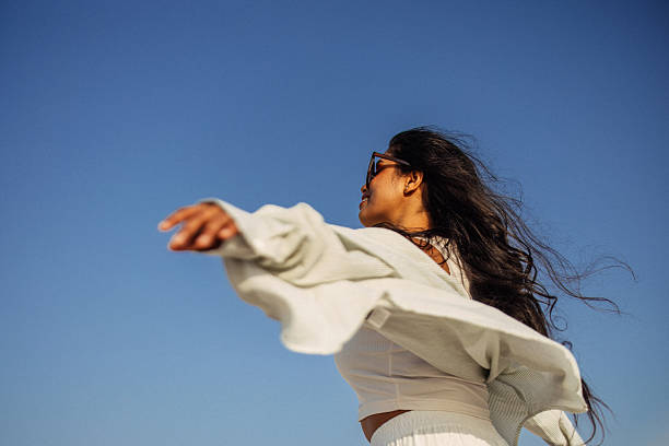 istock Woman enjoys freedom outdoors with arms out in a sunny setting 2216944108