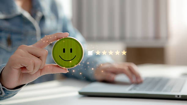 istock Customer satisfaction and feedback concept with hand holding smiley face icon and five-star rating, representing positive review and service evaluation in online survey. 2216951485