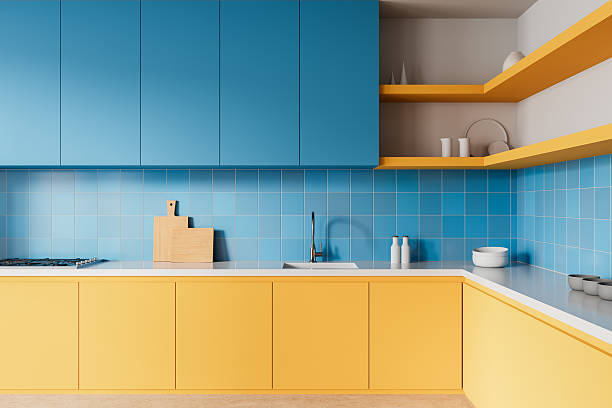 istock Modern kitchen interior with blue and yellow cabinets, tiled backsplash, and minimalist decor on white countertop. Contemporary home design concept. 3D Rendering 2216955626