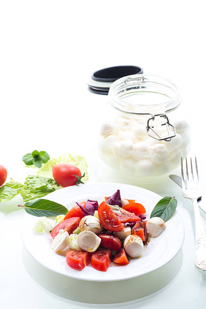 Appetizer with mozzarella, tomatoes and green leaves. isolated on white background.