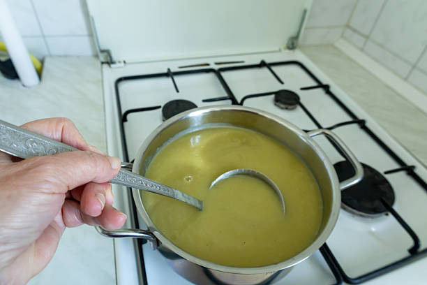 A hand holding a ladle filled with creamy leek soup, emphasizing the warmth and homemade feel of the dish. Perfect for food blogs, recipe tutorials, and cozy cooking content.