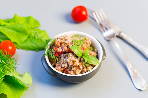 Boiled buckwheat with vegetables on a gray background.