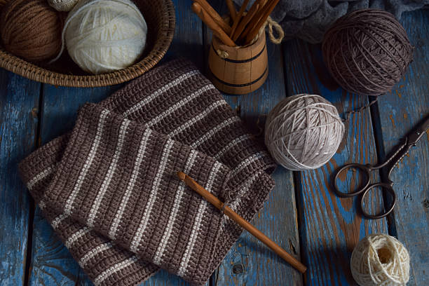 Woolen threads, soft textiles and DIY accessories on a blue wood background. Cozy crafting scene with natural materials and handmade feel. Rustic knitting composition