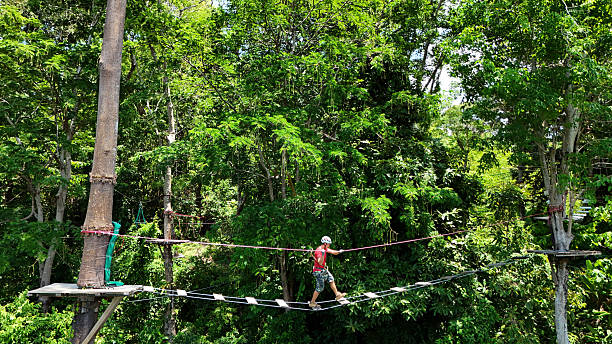 A man is walking across a challenging ropes course in the extreme park