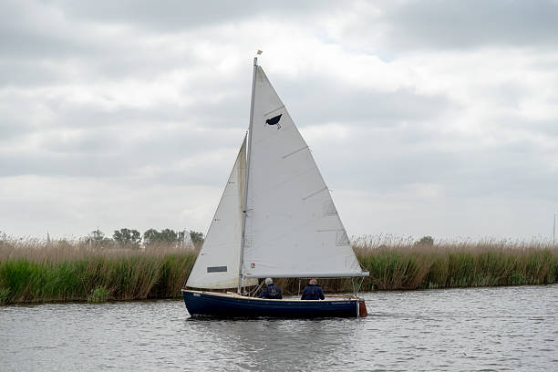 Upton, Norfolk, UK  May 18 2025. Small and wooden sailing boat racing down the River Bure during the 2025 Acle Regatta