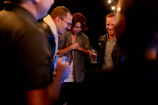 istock Group of friends enjoying a lively evening gathering with drinks and laughter under decorative string lights 2216964700