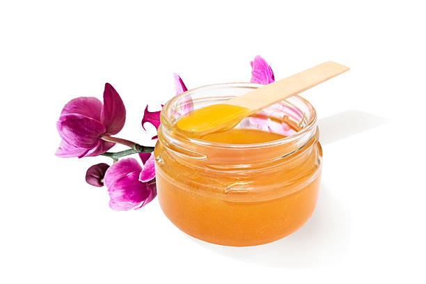 istock Liquid sugar paste for hair removal in bowl with orchid flower on white background. 2216965964