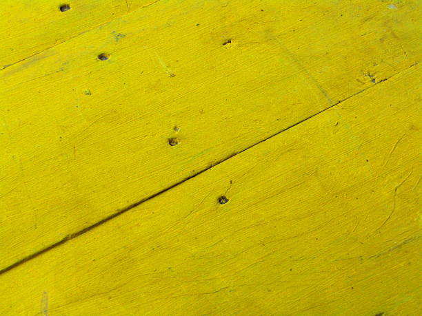 Vivid yellow wood surface with aged marks, demonstrating texture and color vibrancy, suitable for backgrounds, art, or design concepts in an eclectic and bright setting.