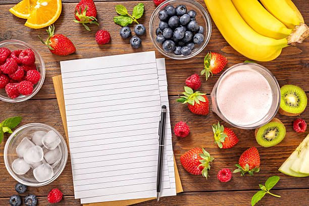 Top view of fresh different fruits for cooking smoothies with notebook  on rustic wooden table. Healthy eating diet planning menu or recipe background with copy space