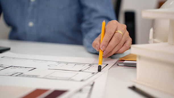 istock Architect Hand Drawing Blueprint with Pencil for Construction Planning Senior Asian Hand Inspecting Blueprint Architect Drawing Design Plan 2216972715
