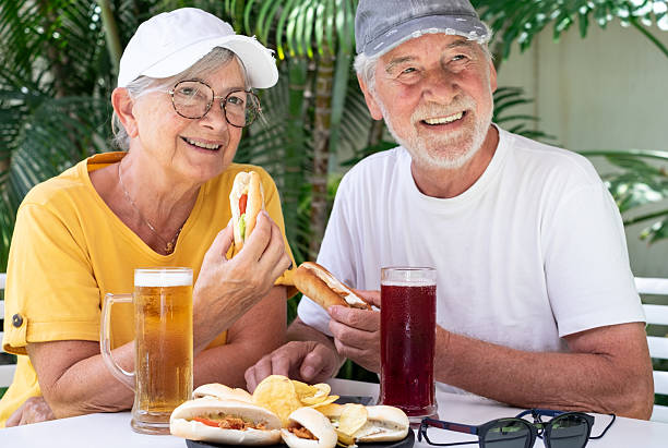 istock Happy Senior Couple Enjoying Drinks and Snacks Outdoors with beer, sandwiches, and chips. Atmosphere perfect for promoting retirement lifestyles, leisure, and healthy aging. 2216980603
