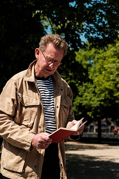 istock Senior man reading a book in a park 2216981295