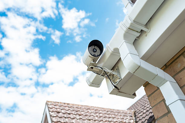 Homeowner installed night and day cctv camera mounted at the corner of a gutter on a price house. stock photo