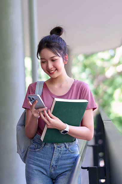 istock Young Asian Woman Student Using Smartphone Holding Book on University Campus Educational Lifestyle for Academic Success 2216984637