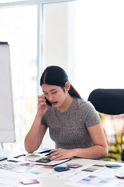 istock Interior designer making business call while working on color and material selection at design studio desk 2216985895
