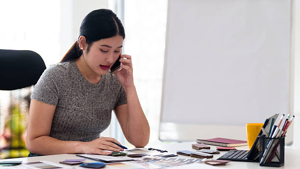 istock Interior designer making business call while working on color and material selection at design studio desk 2216985897