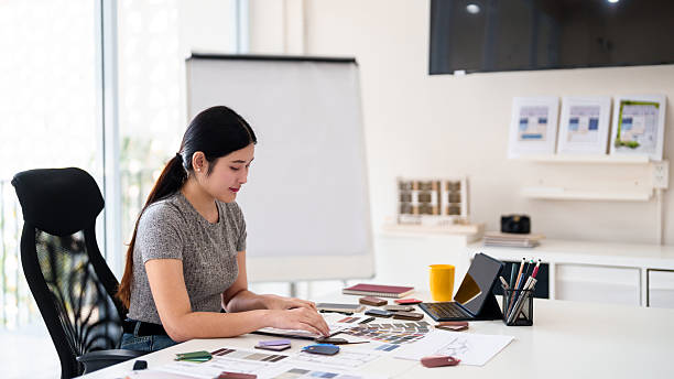 istock Focused interior designer planning color concepts and working with material samples at design desk 2216985902