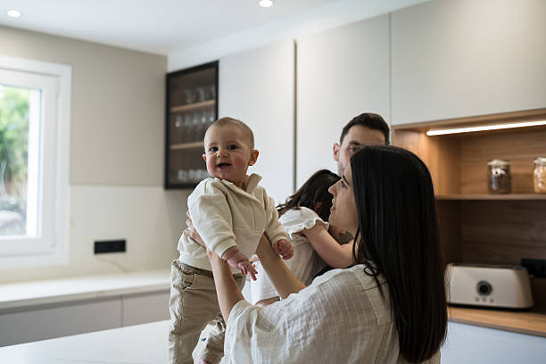 istock Happy family lifting baby in modern kitchen 2216987109