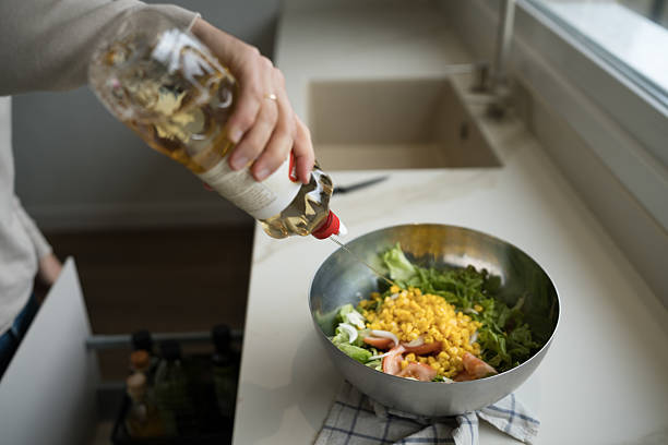 Chef pouring apple vinegar into a bowl filled with fresh salad ingredients in a modern kitchen, crafting a healthy and delicious meal rich in vibrant flavors and nutrients