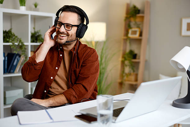 istock Smiling businessman wearing headset talking with customer online, working remotely from home office using laptop computer 2216990097