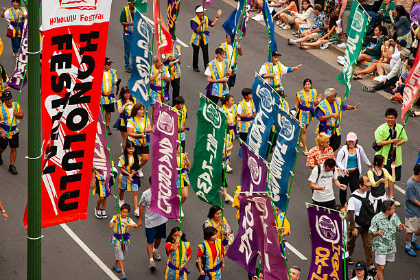 Honolulu, Hawaii, March 12, 2006:  The street at the Honolulu Festival Parade bursts with color and cultural energy.  Performers march proudly down Kalakaua Avenue, surrounded by cheering crowds lining the sidewalk.