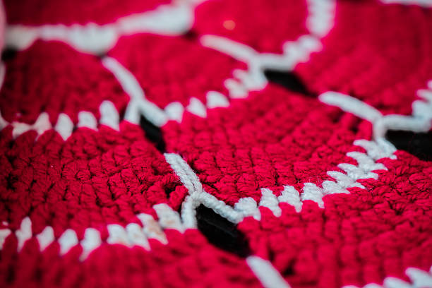 A person’s hand (that has pearl nails color) is holding a red decorative glove against the blue table background. The idea is that we can trust our hands if we keep them warm with the help of gloves. During the winter time when is freezing there is no help if our hands are frozen. Located in Corona California. December 2025.