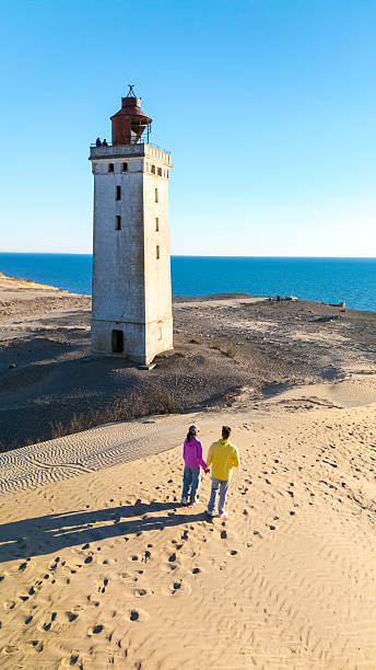 istock Couple exploring the sandy beach near ancient lighthouse in Denmark on a sunny afternoon 2216992756