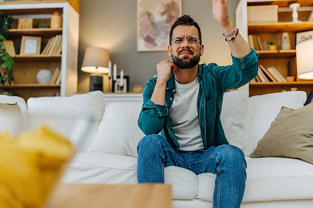 istock Frustrated young man watching tv and feeling annoyed by what he sees 2216997789