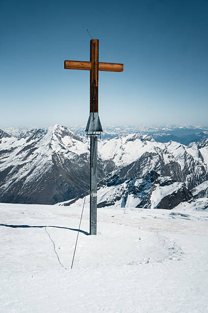 Cross on mountain top, snowcapped mountain ranges below, Saas Fee, Valais Canton, Swiss Alps