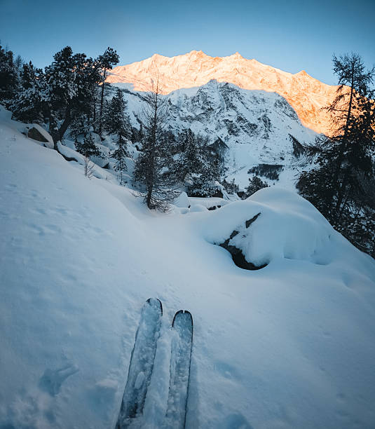 Skis and alpenglow on snowcapped mountains, Saas Fee, Valais Canton, Swiss Alps