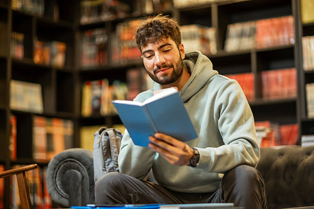 istock Male Student Studying from Book in Library 2216999479