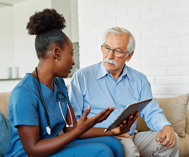 istock nurse doctor senior care tablet computer technology showing caregiver help assistence retirement home nursing elderly woman african american black happy laughing man 2217000028