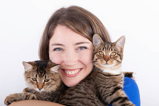 istock Attractive young woman holding two cats against white background. 2217002626