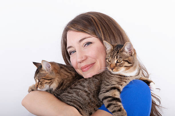istock Attractive young woman holding two cats against white background. 2217002649
