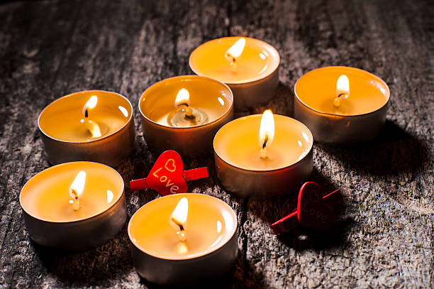 Tealight candles shine steadily on the brown background. The flame of each candle creates a pleasant contrast in the darkness. The tealights add a soft glow to a special moment.