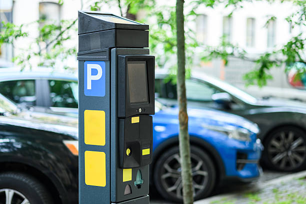 istock A parking meter is positioned on the sidewalk, surrounded by parked cars and greenery, indicating an urban setting 2217003413