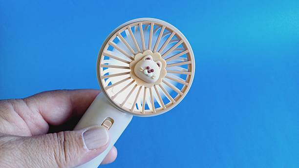 istock A woman holding a battery-powered fan. Fan. 2217005281
