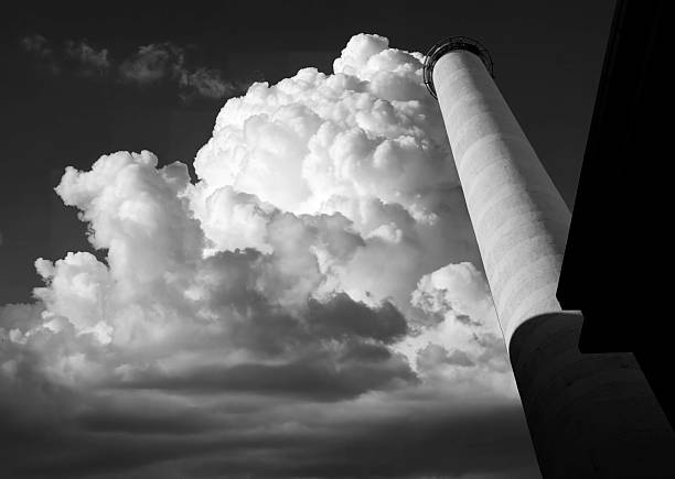 Verticalism in architecture. Dramatic black and white image of a disused tall, sky reaching chimney of an old textile mill standing out starkly against dramatic cloud formation.