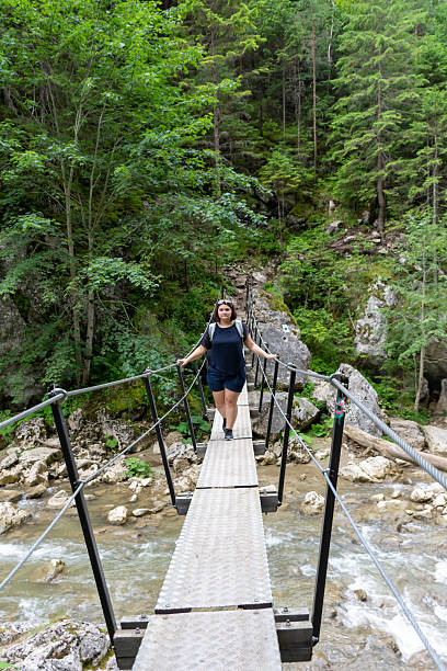 istock A woman is walking leisurely across a bridge over a river 2217006184