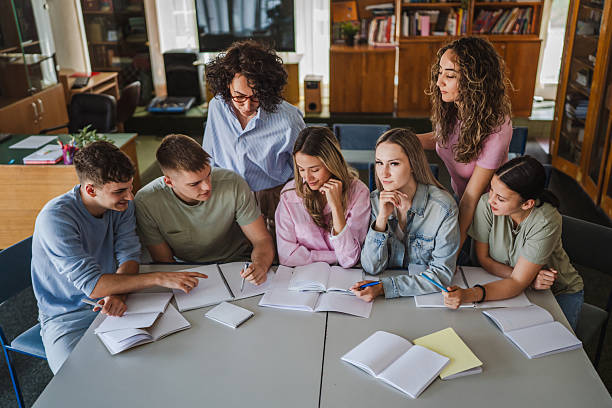 istock Group of high school students work on project with teacher in library 2217009561